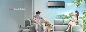 Mladi par sjedi na kauču u dnevnom boravku sa svojim psom dok klima uređaj LG AirCare Complete System hladi prostor.