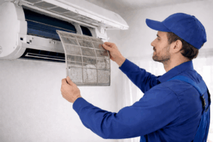 Klima uređaji 2026. novosti - Majstor čisti filter klima uređaja uklanjanjem zaprljane rešetke iz unutarnje jedinice tijekom redovnog servisa.